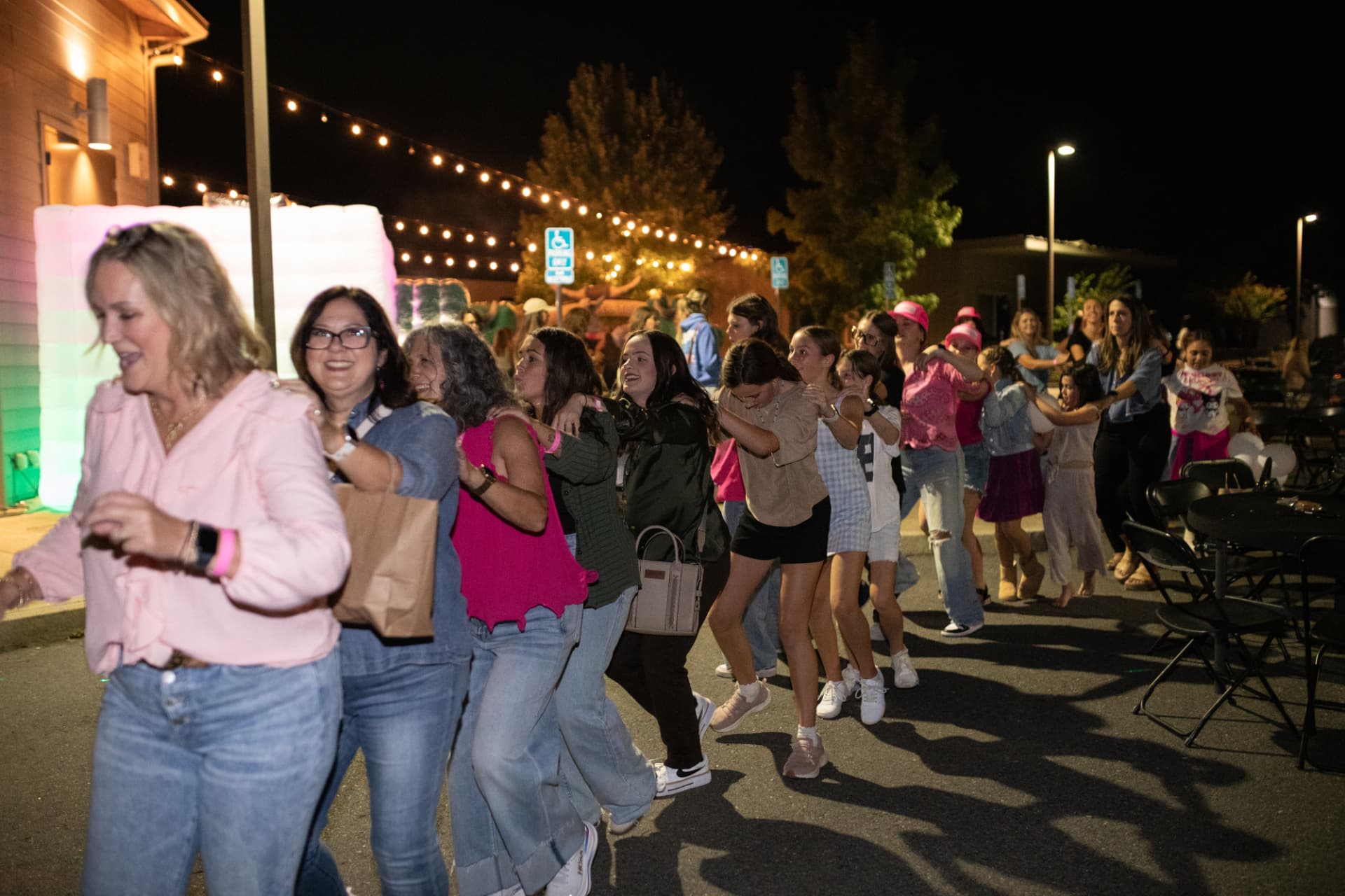 Women dancing in a conga line under string lights at BLUSH