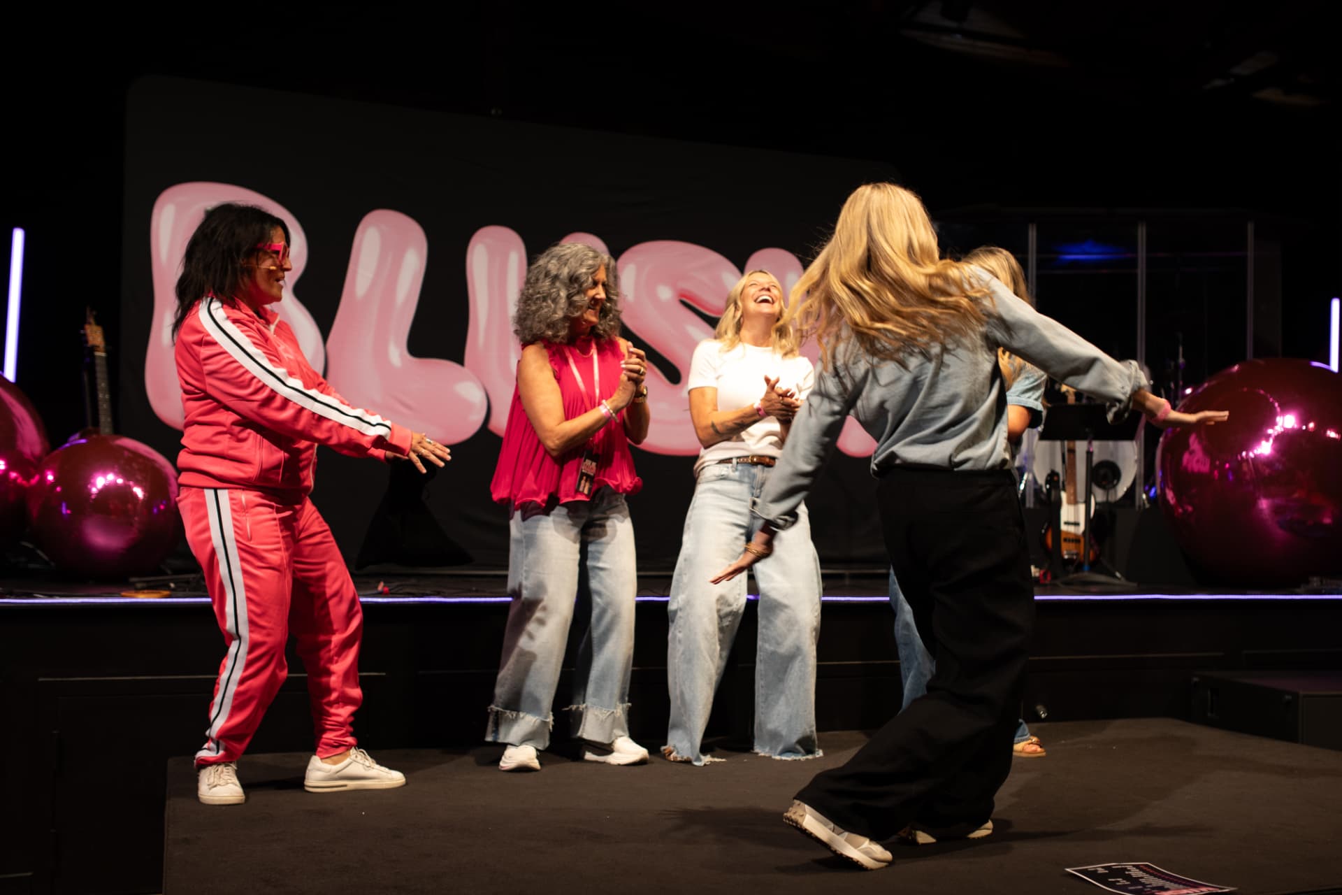 Women laughing and dancing together on stage at BLUSH