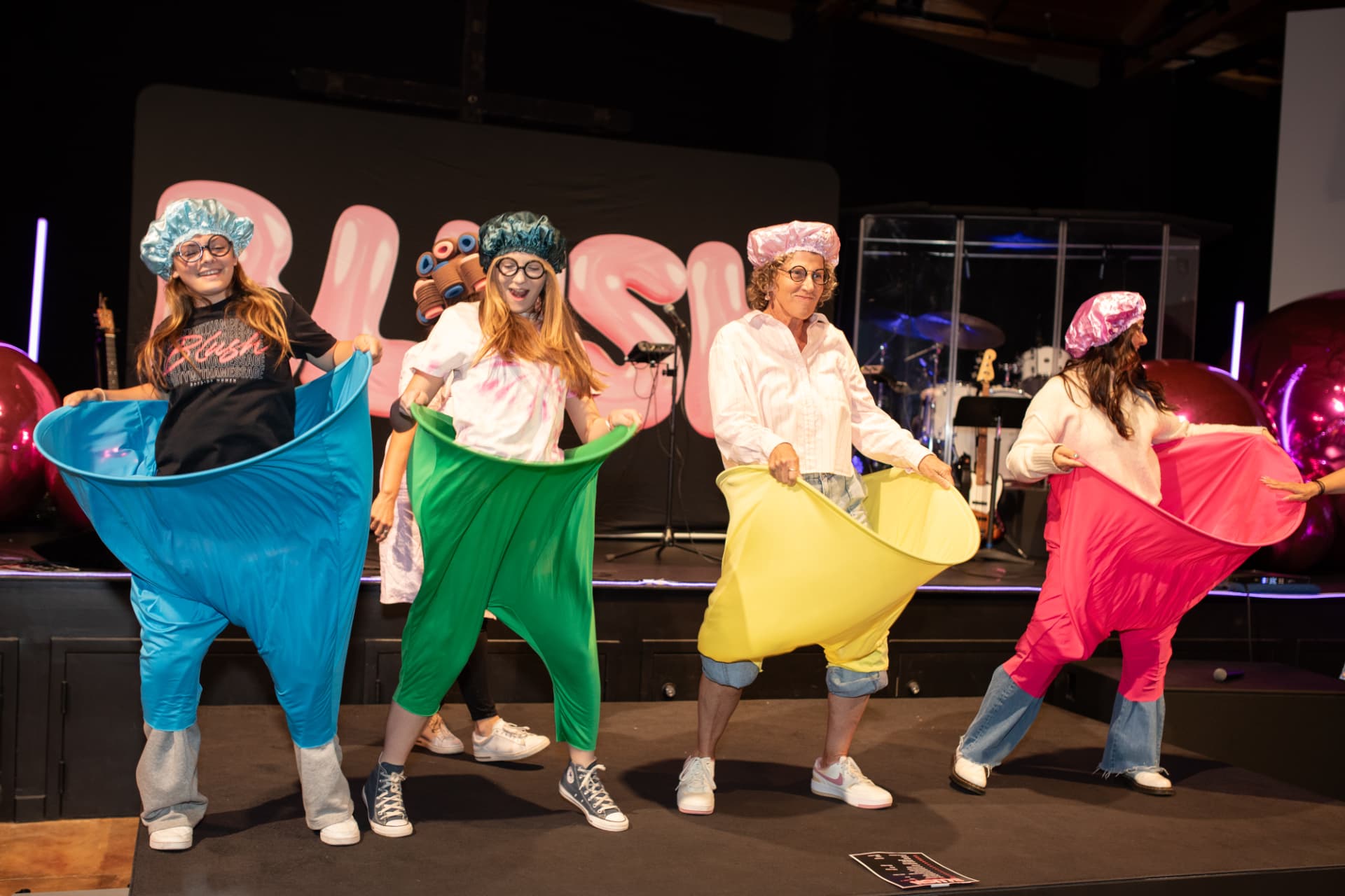 Women laughing in colorful inflatable costumes on stage at BLUSH